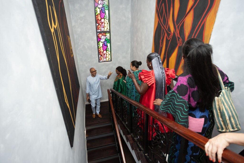 Visitors climb the staircase inside the Black Muse Residence, past artworks and a stained-glass window